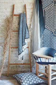 a wooden ladder leaning against a brick wall next to pillows and blankets on the floor