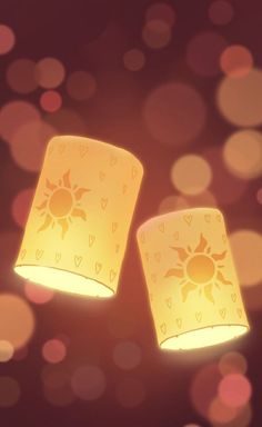 two yellow lamps with hearts and sun designs on them are shining brightly in the dark