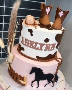 a birthday cake decorated with cowboy boots and a horse on the side, sitting on top of a table