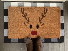 someone is standing in front of a door mat with reindeer's head on it