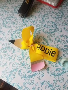 a pair of shoes sitting on top of a table next to a yellow ribbon with the word abie written on it