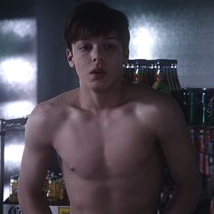 a shirtless young man standing in front of a refrigerator