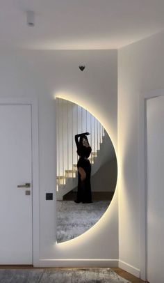 a woman standing in front of a round mirror on the wall next to a doorway