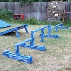 several blue benches sitting in the grass near a fence