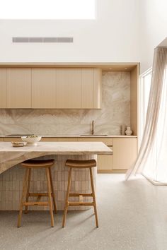 two stools sit at the center of a kitchen island in front of a window