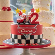 two cars are on top of a cake with stars and stripes around the edges that spell out 2