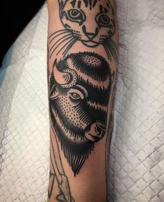 a black and white tattoo on the arm of a person with a cat head in it