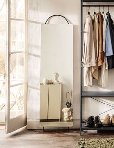 an open closet with clothes and shoes hanging on the rack, next to a window