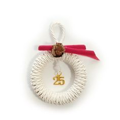 a white bracelet with a red ribbon and a pine cone hanging from it's end