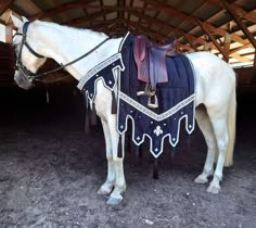 a white horse wearing a blue blanket and saddle