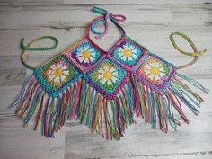 a multicolored crocheted bag hanging on a wooden floor with a string attached to it