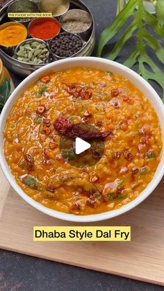 a bowl filled with food sitting on top of a wooden cutting board next to spices