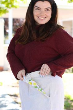 a woman is smiling while holding onto her purse in front of the camera, with one hand on her hip