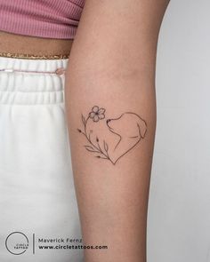 a woman's arm with a small tattoo of a dog and flowers on it