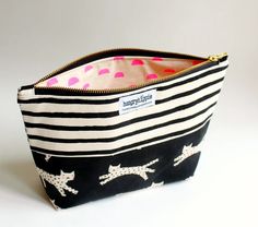 a black and white striped bag with pink polka dots on the bottom has cats printed on it