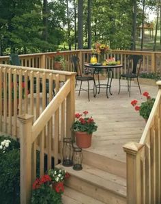 a wooden deck with potted plants and flowers on the steps leading up to an outdoor dining area