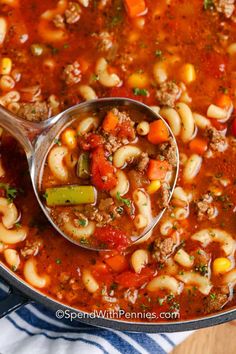 a ladle full of pasta soup with meat and vegetables