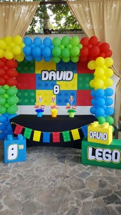 a birthday decoration with balloons and legos on the ground in front of a backdrop