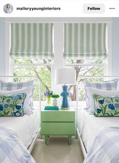 a bedroom with two beds and green nightstands in front of striped curtains on the windows