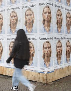 a person walking past a large poster with images of women on it's sides