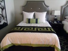 a hotel room with two beds, one has a black and green comforter on it