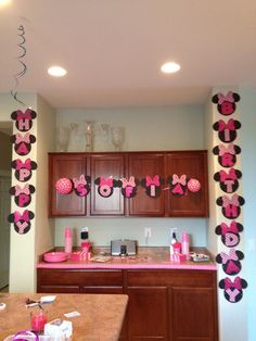 a kitchen decorated with pink and black minnie mouse decorations on the wall, along with hanging streamers that say i love you