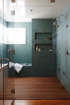 a bath room with a shower and a wooden floor next to a window on the wall