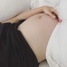 a pregnant woman laying on top of a bed