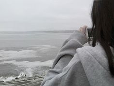 a woman taking a photo of the ocean with her cell phone