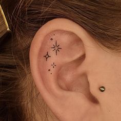 a woman's ear with three small stars on it and one behind the ear