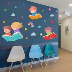 the children's room is decorated with blue walls and colorful wall decals, along with white chairs