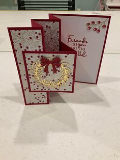 three christmas cards on a table, one is red and the other has white paper