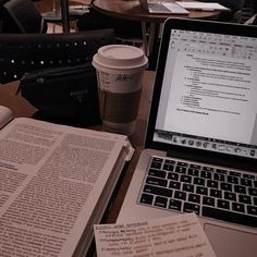 a laptop computer sitting on top of a wooden table next to a cup of coffee