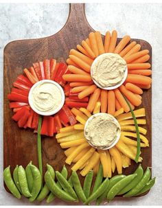 carrots, celery, and peppers on a cutting board with dip in the middle