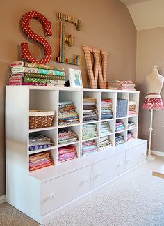 a room with many different types of fabric on the shelves and lamps in front of it