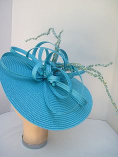 "* This design can be worn on either side of the head and has a sophisticated side tilt. It features a monocromatic color scheme in a tantalizing turquoise. The center of the hat form has a burst of looped and swirled braiding accented by enhanced clusters of matching berries and curly berry twigs. * On an 12\" round flat hat form this is a great design for spring and summer and will also go right into the fall and winter as well. * It is light weight, balanced and comfortable on a white satin c Blue Fitted Fascinator For Beach, Turquoise Fascinator For Spring Party, Elegant Turquoise Fascinator For Kentucky Derby, Turquoise Spring Party Fascinator, Turquoise Fitted Party Hat, Spring Party Turquoise Fascinator, Turquoise Fitted Hat For Party, Fitted Turquoise Hat For Party, Turquoise Fascinator For Kentucky Derby