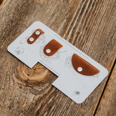 two pieces of brown leather sitting on top of a wooden table next to each other