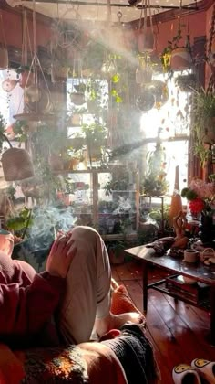 a person sitting on a couch in a room with lots of potted plants