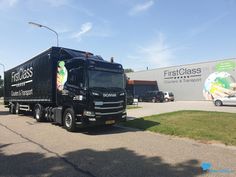 a black truck is parked in front of a building with a sign that says first class