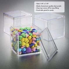 two clear boxes filled with colorful candies on top of a silver surface and one is empty