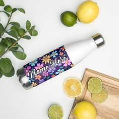 a bottle of lemonade next to sliced limes on a cutting board with leaves