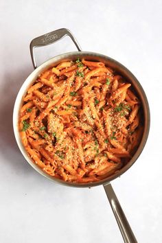 a pan filled with pasta and sauce on top of a white table next to a fork