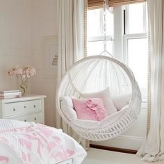 a white hammock hanging in a bedroom next to a bed with pink pillows