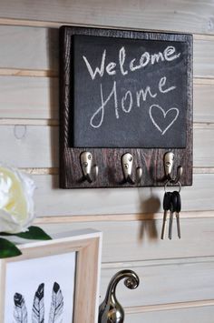 a welcome home sign hanging on the wall next to keys and a key holder with hooks