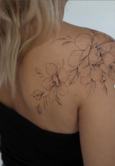 the back of a woman's shoulder with flowers tattooed on her left arm and chest