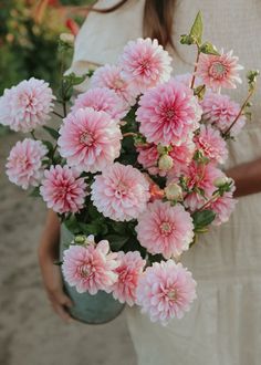 a woman holding a vase filled with pink flowers