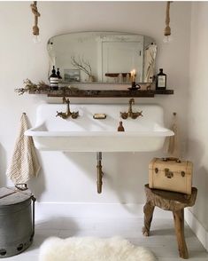 a white sink sitting under a bathroom mirror next to a trash can and luggage bag