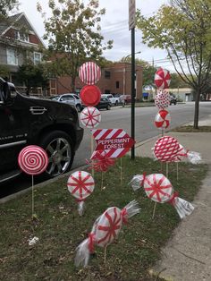 some candy lollipops are on the grass near a street sign and cars