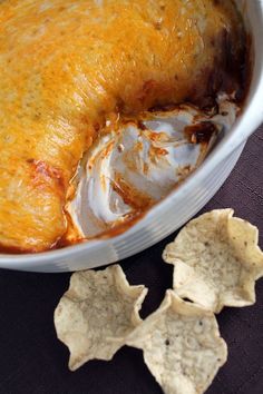 a casserole dish with cheese and tortilla chips on the side, ready to be eaten