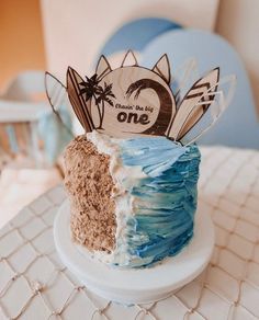 a blue and white cake sitting on top of a table next to a wooden sign